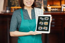 Cropped image of smiling waitress showing new menu on tablet computer
